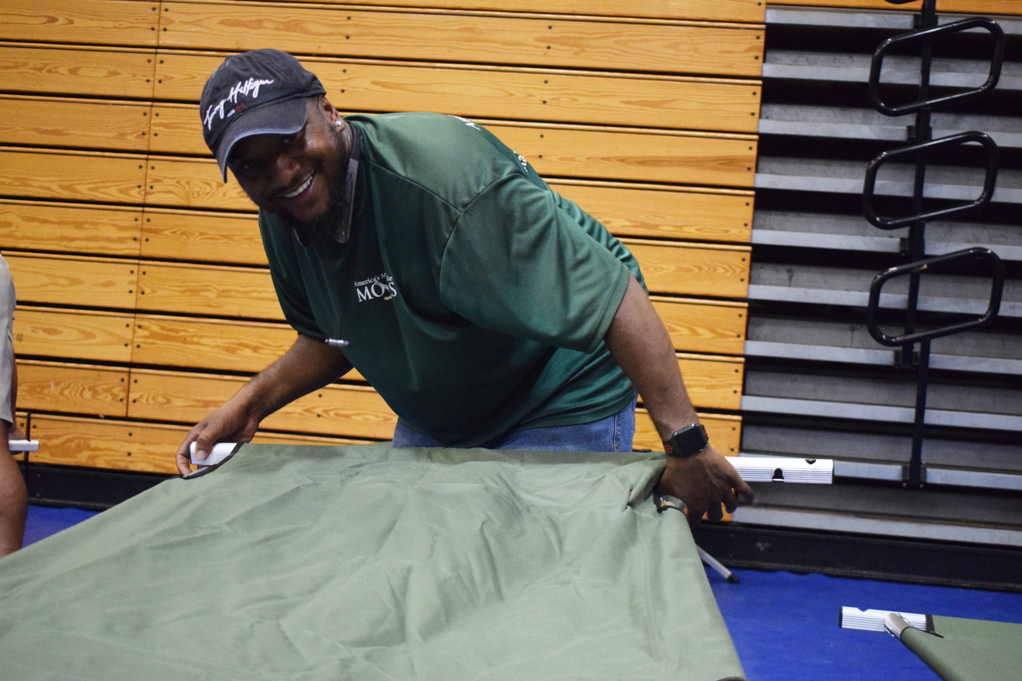 Kirey Whitehead with AMR Movers helps set up cots at R. Dan Nolan Middle School. (Photo by Liz Ramos)