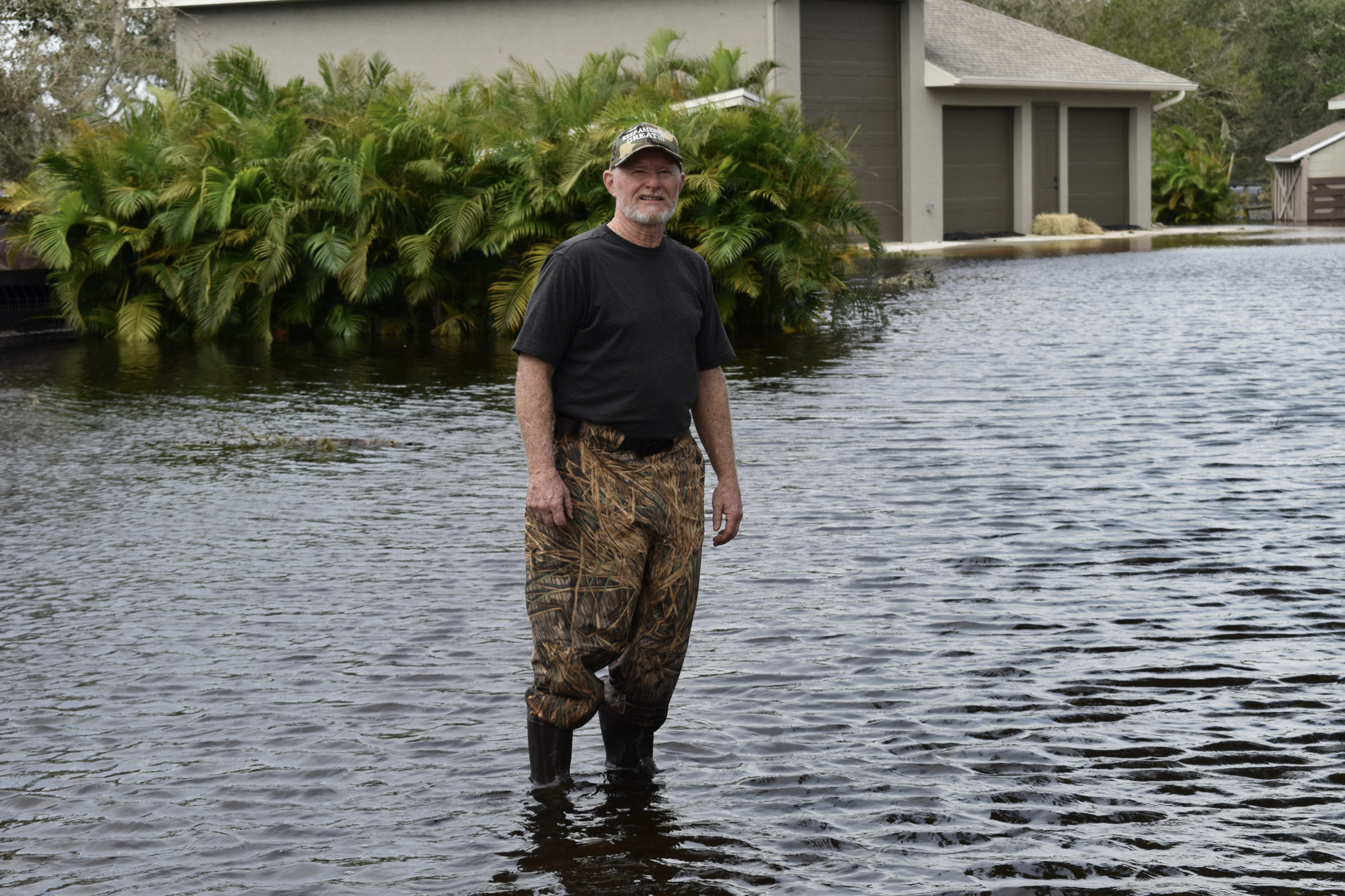 Saddlebag Creek resident Regis Champ stands in the water that flooded his home. (Photo by Ian Swaby)