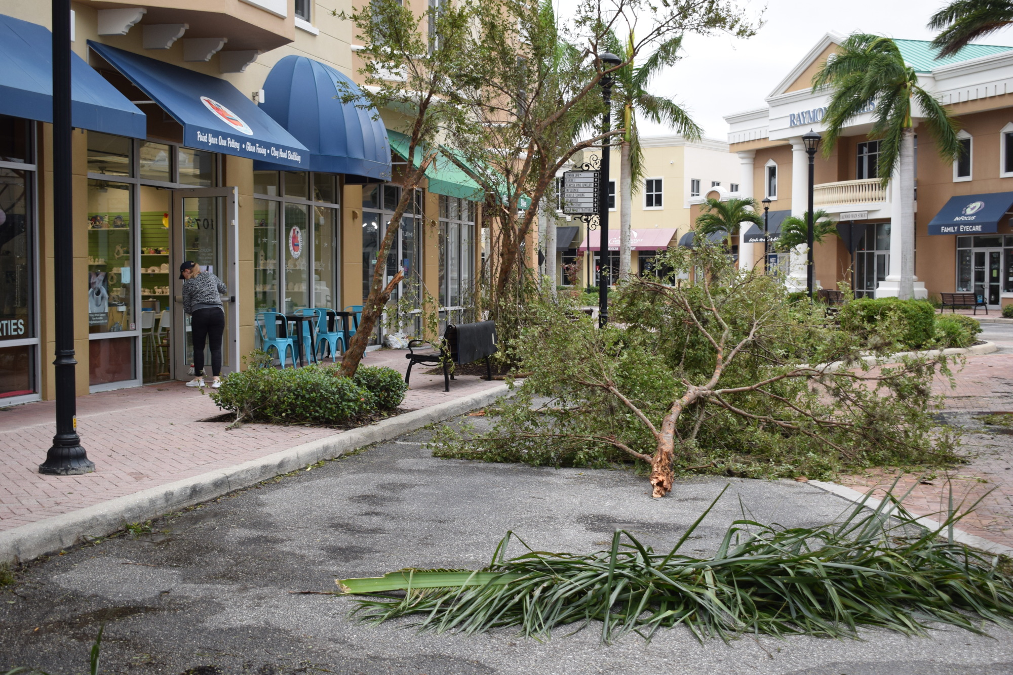 Joann Kavanaugh, the owner of Arts A Blaze at Main Street at Lakewood Ranch, sweeps water out of her store in front of the scattered debris on the street.  (Photo by Jay Heater)