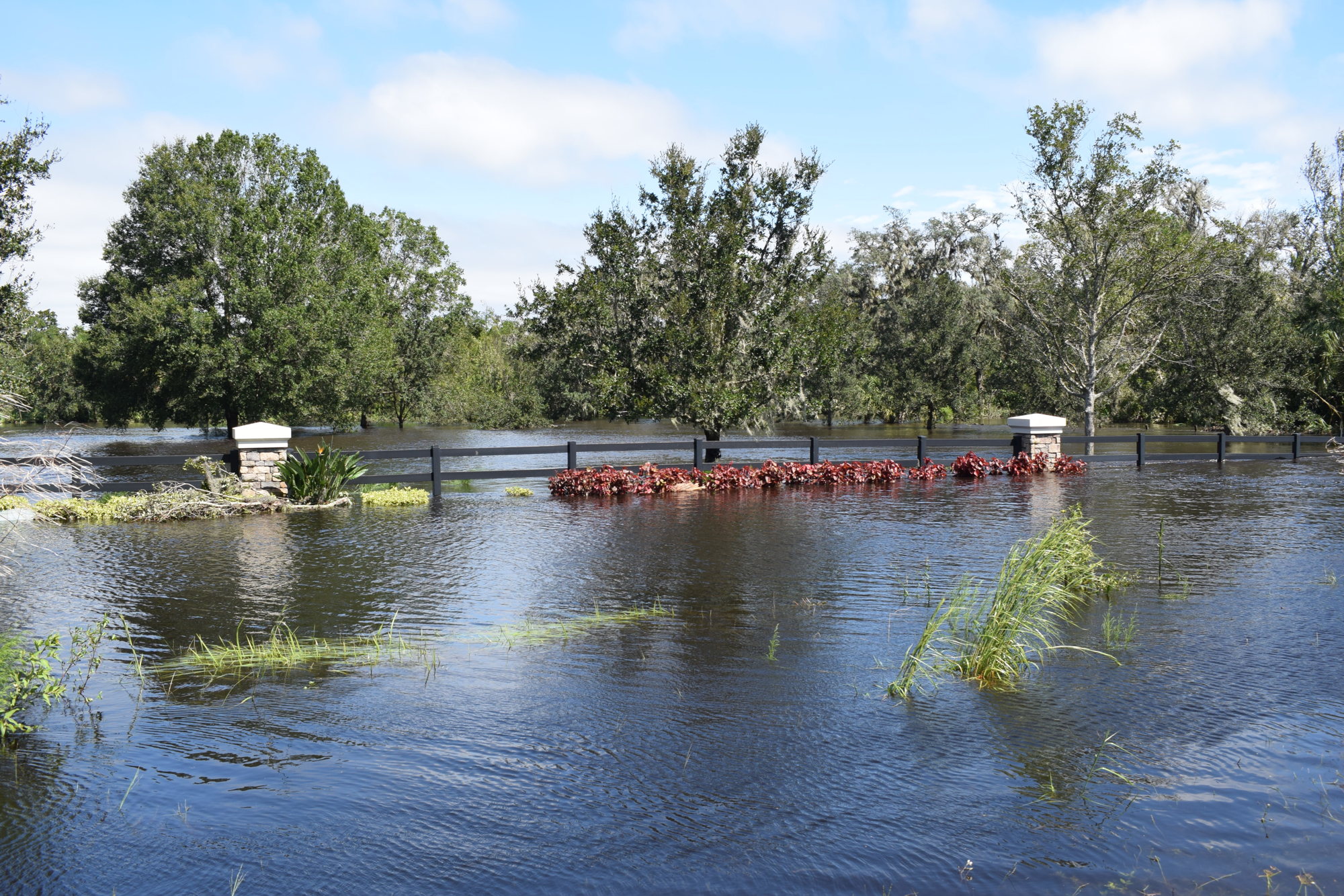 A neighborhood fence along Upper Manatee River Road in East County is buried by water. (Photo by Jay Heater)