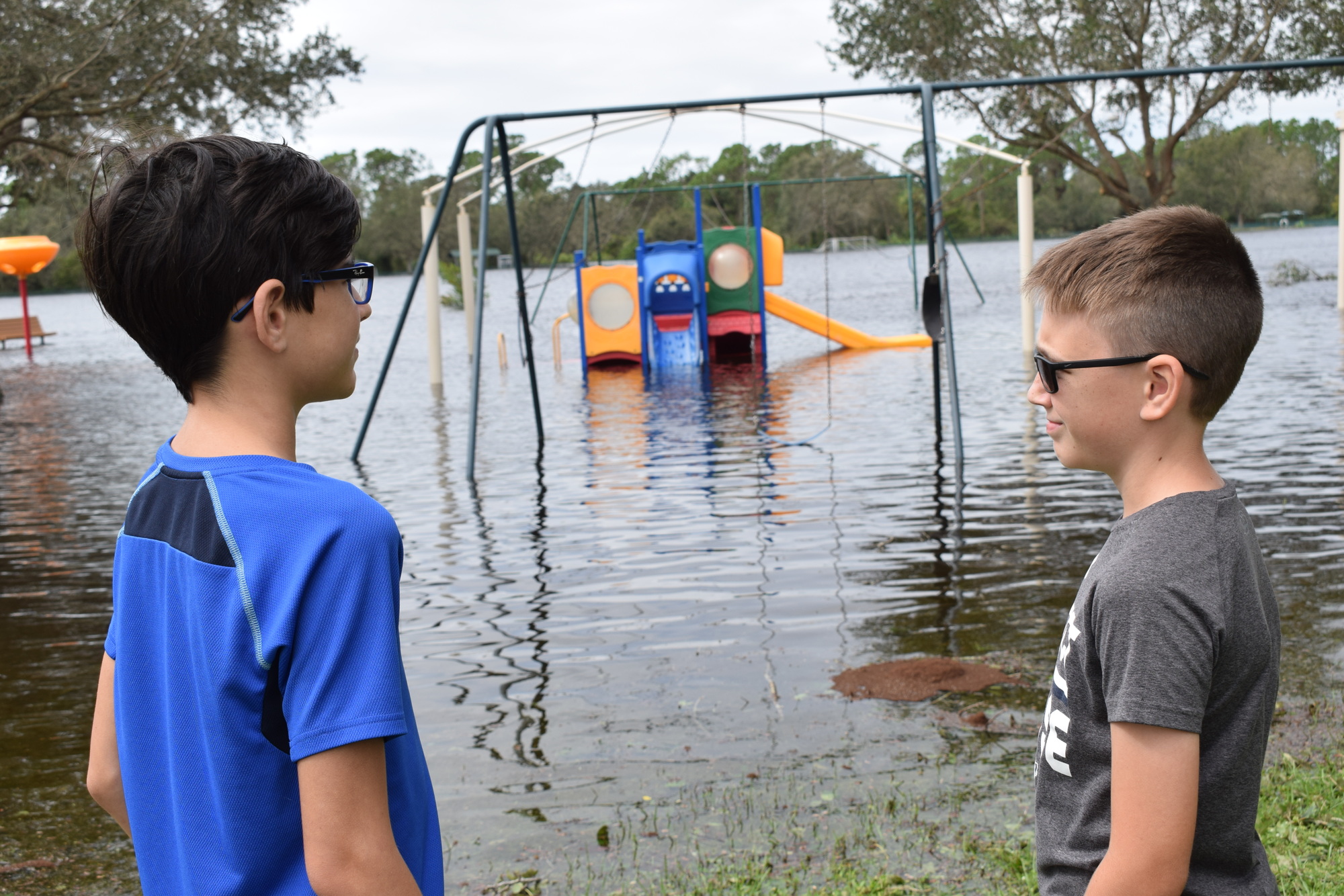 A.J. Sirek, 12, and Noah Sirek, 10, check out the flooded playground at Greenbrook Adventure Park in Lakewood Ranch around 12:45 p.m. Thursday.  (Photo by Jay Heater)