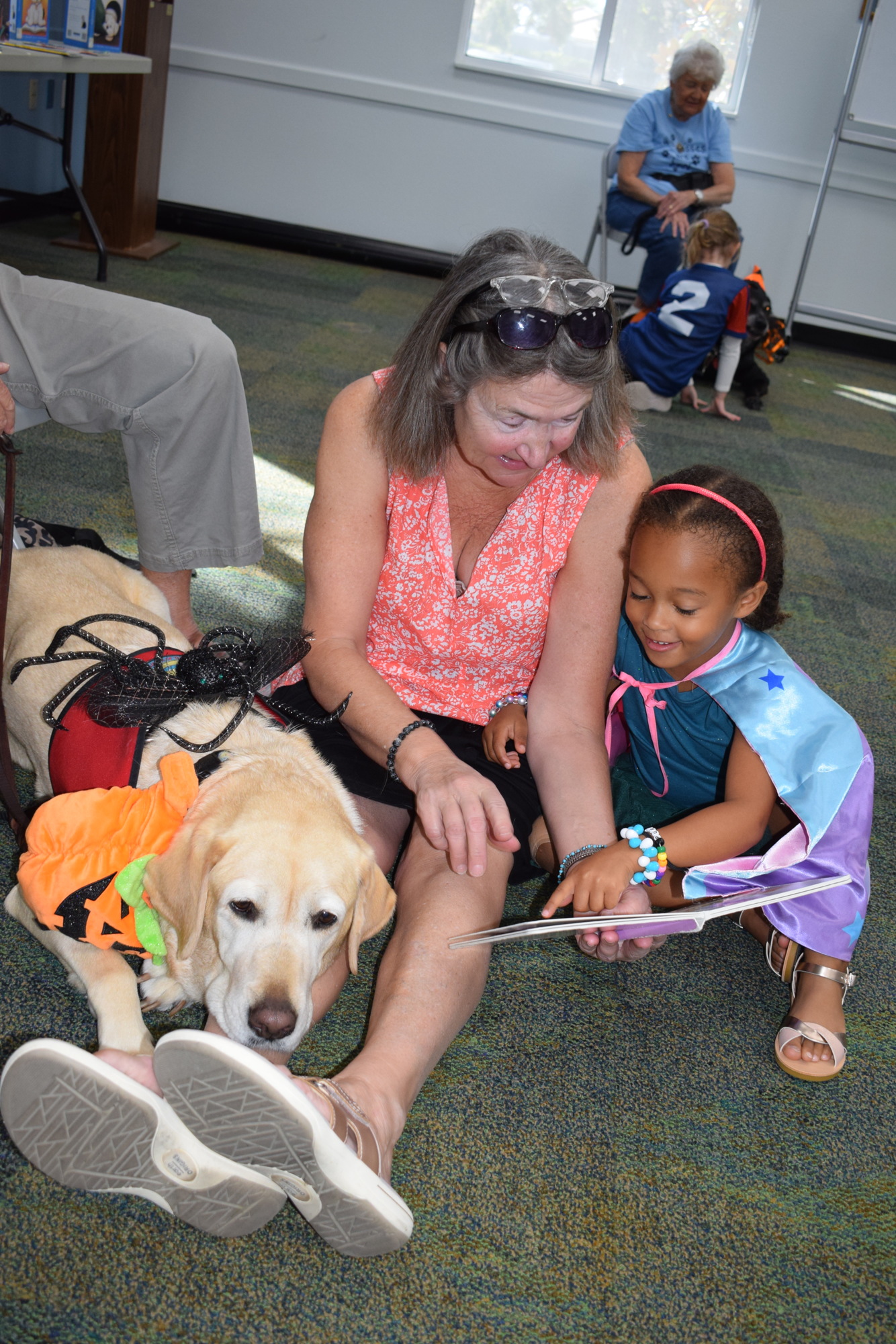 Marjorie, a Lab brought to Read 2 Dogs by Mary Scharf, and grandma Sandi Jossi listen to Evy Esdelle read.
