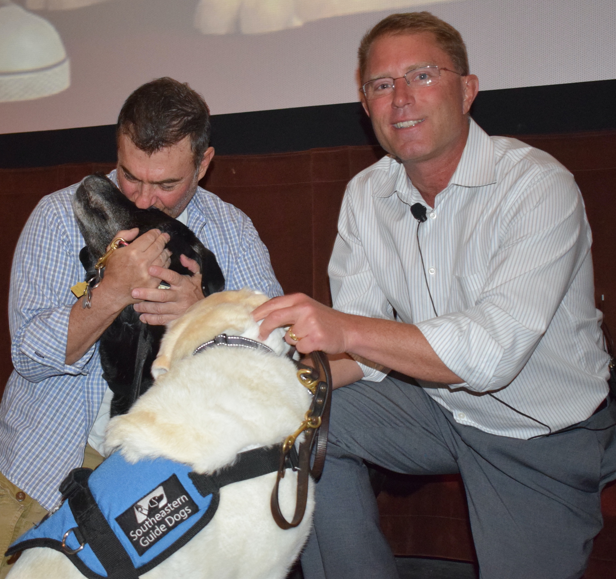 Dave Caras hugs his Southeastern Guide Dog, Bobb, and Morgan Watt pets Foley. The dogs have made a huge difference in the lives of the veterans. (Photo by Jay Heater)