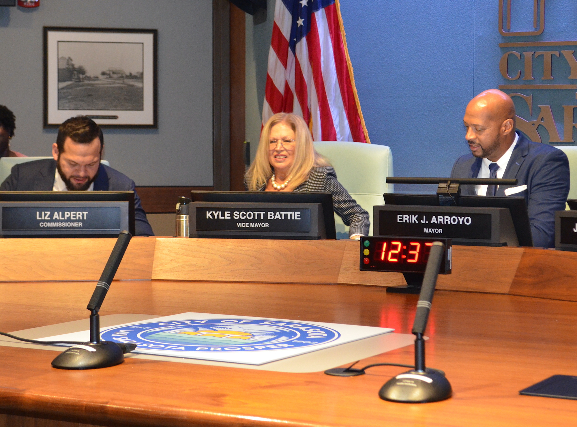 From left, former Sarasota mayor Erik Arroyo, new vice mayor Liz Alpert and new mayor Kyle Battie swap seats at the dais. Changing the nameplates in front of their seats will come later. (Andrew Warfield)