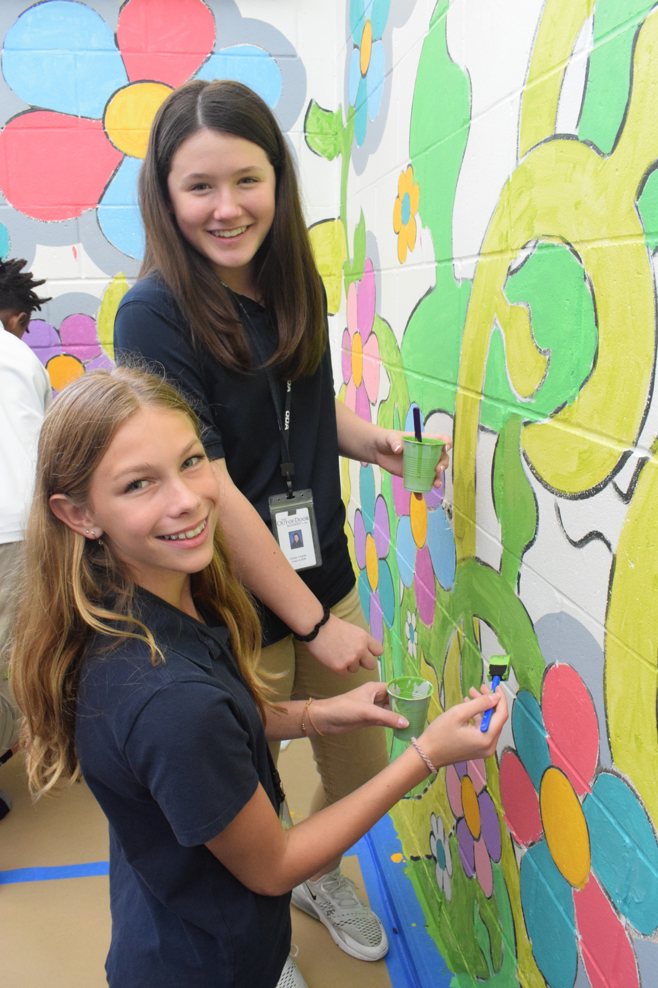 Seventh graders Emmy Coachys and Gabi Schauenberg add another coat of green to the stem vine of the flowers. (Photos by Liz Ramos)
