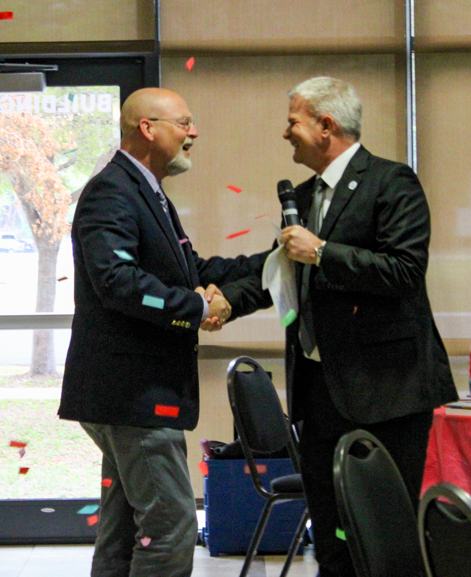 Stephen Covert shakes the hand of Sarasota County Schools Superintendent Brennan Asplen amid a flurry of confetti. (Courtesy image)